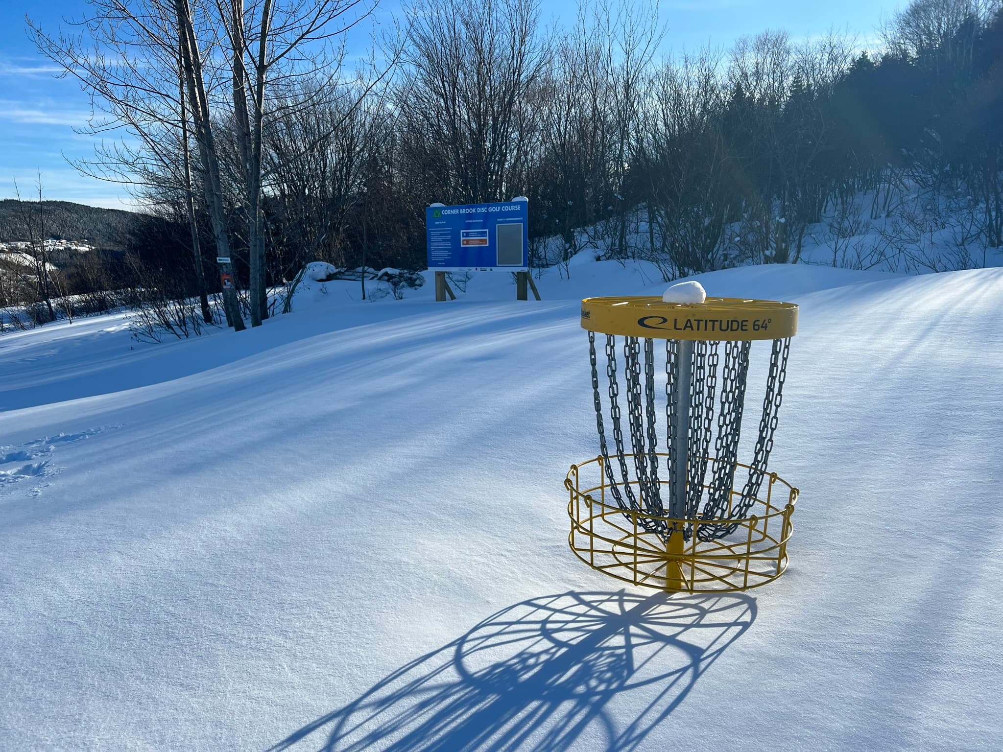 A photograph of the practice basket and course sign. A lot of snow is on the ground.